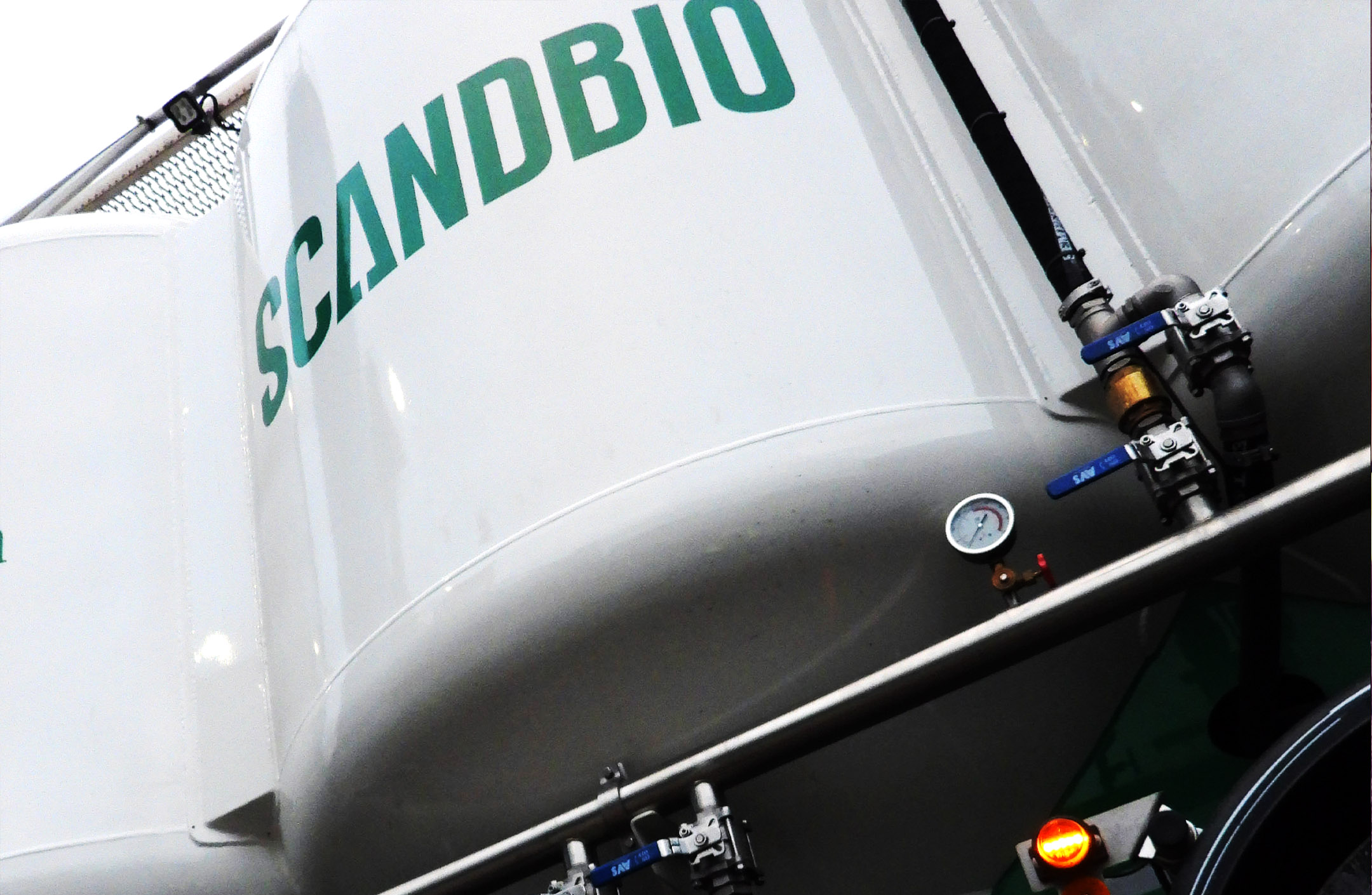 Närbild på bulkkula på pelletslastbil. Scandbios logotyp i grönt mot vit bakgrund.